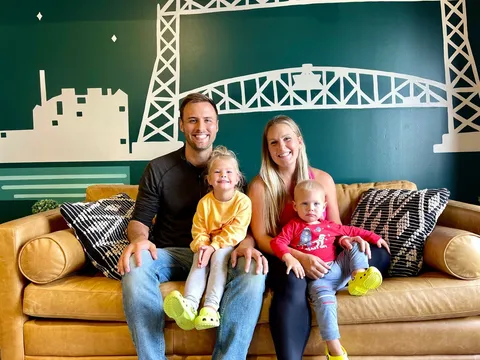 The Brickson family on a leather sofa in front of an Aerial Lift Bridge mural