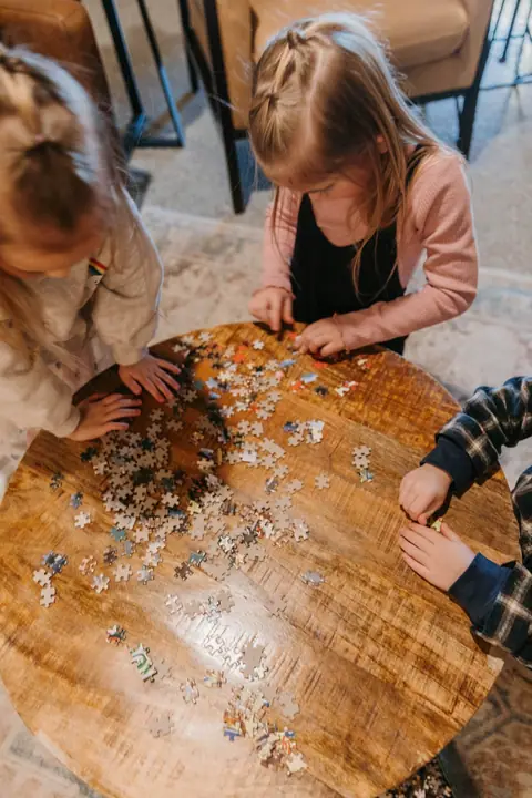 Kids working on a jigsaw puzzle on a round wood table in a Brix condo