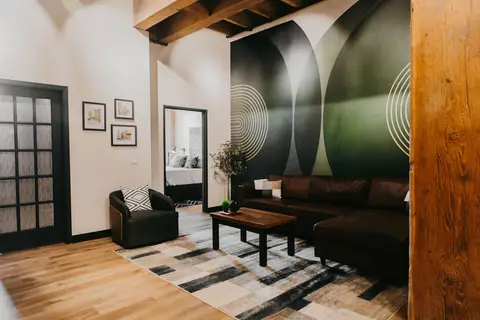 Bridgeman Loft living room with dark leather sofas and a green mural wall